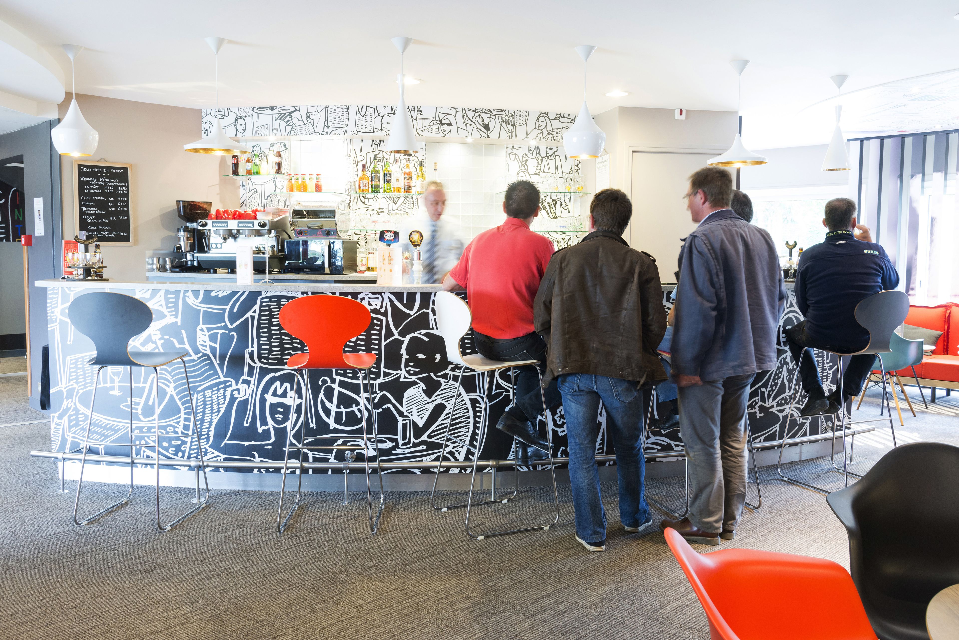 A bar area with a counter, stools, and a menu board.