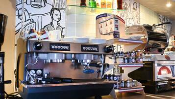 Une machine à café dotée d’un mousseur à lait, d’un moulin à café et d’un présentoir où sont exposés des grains de café et des pots d’assaisonnements.