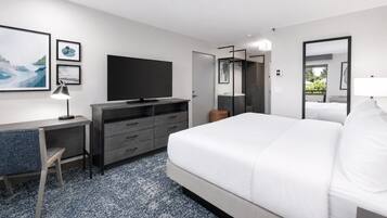 Una habitación de hotel con cama, escritorio, computadora, televisor y armario.