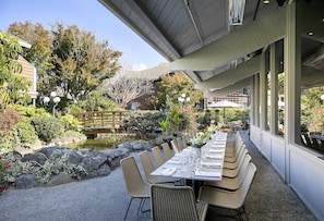 An outdoor dining area with tables and chairs, surrounded by a garden with rocks and plants. - Seacliff Inn Aptos, Tapestry Collection by Hilton (Aptos)