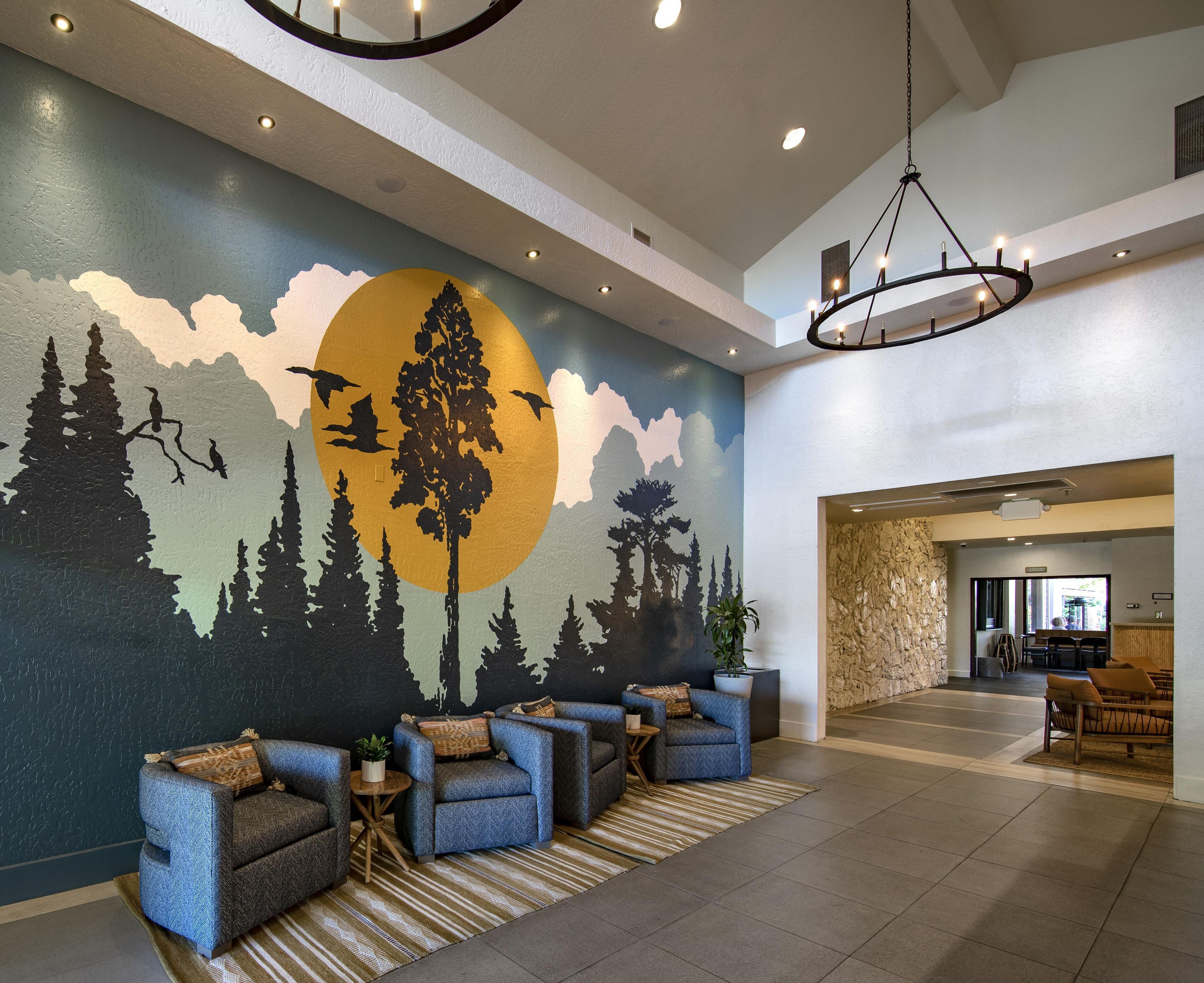 A lobby with a mural of a forest scene, seating area with sofas and a coffee table, and a stone wall.