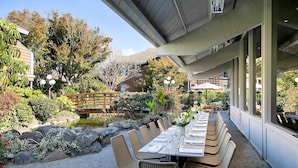 An outdoor dining area with tables set for guests, surrounded by a garden with a pond and various plants. - Seacliff Inn Aptos, Tapestry Collection by Hilton (Aptos)