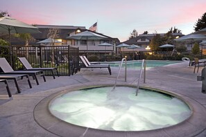 A pool area with lounge chairs and umbrellas, surrounded by buildings with American flags. - Seacliff Inn Aptos, Tapestry Collection by Hilton (Aptos)