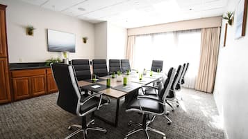 Uma sala de conferências com uma grande mesa, cadeiras pretas e vista para o oceano pelas janelas.