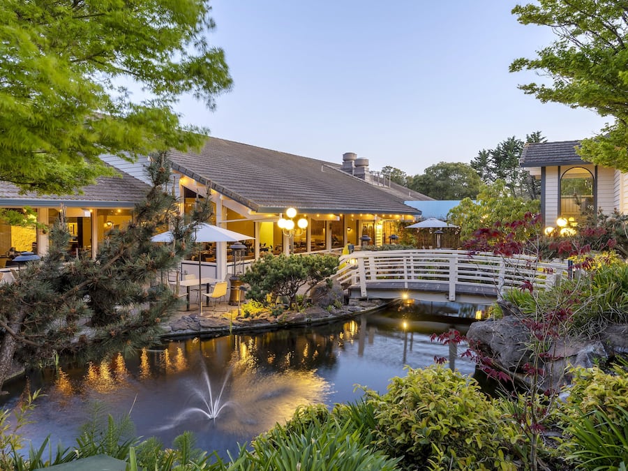 A lakeside hotel with outdoor seating and a bridge over the water.