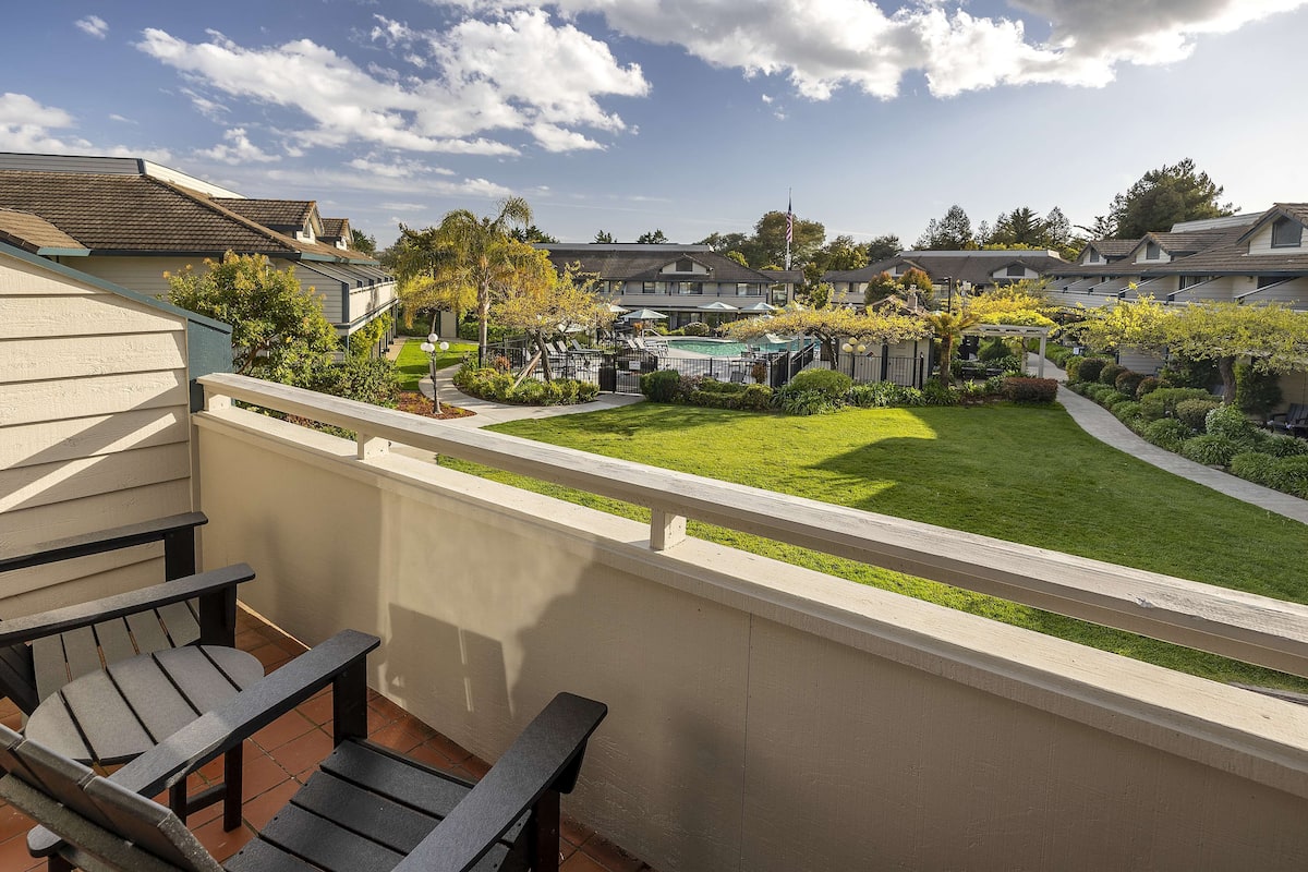 A residential area with a swimming pool, patio chairs, and a well-maintained lawn.