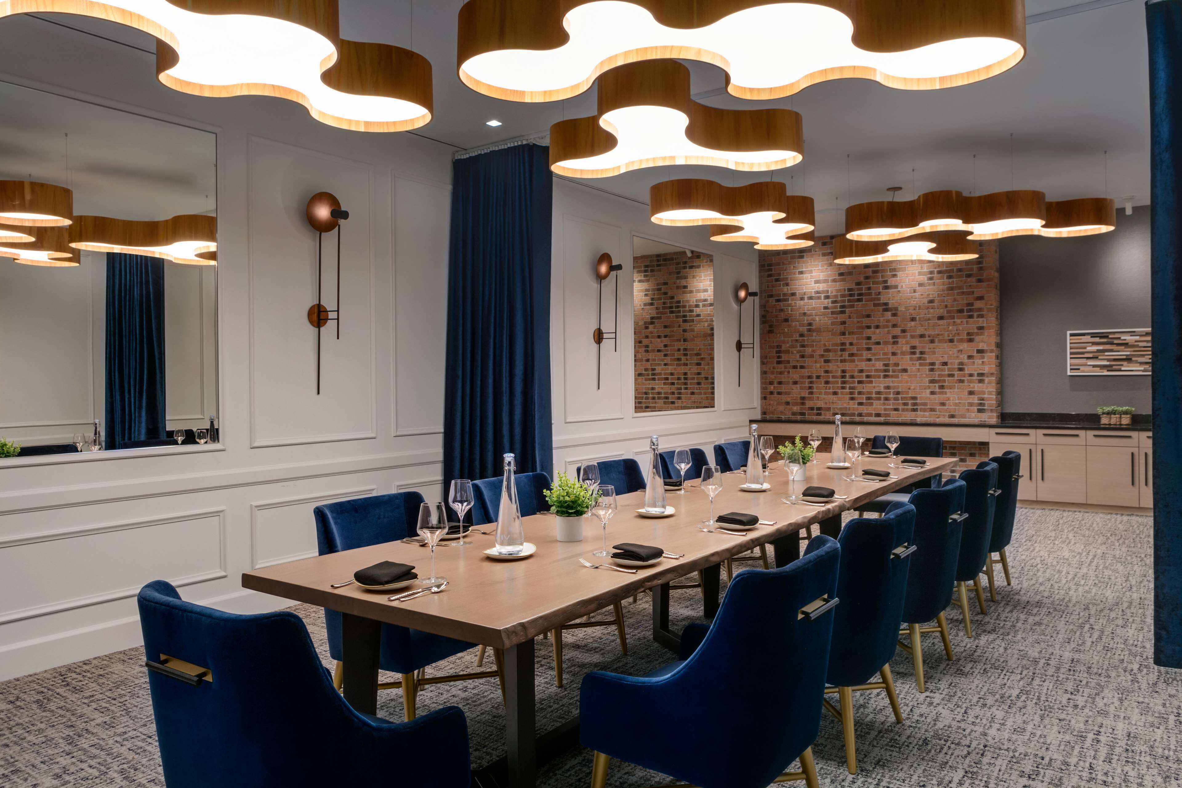 A conference room with a long table, blue chairs, and modern pendant lighting.