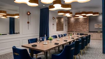 A conference room with a long table, blue chairs, and modern pendant lighting.