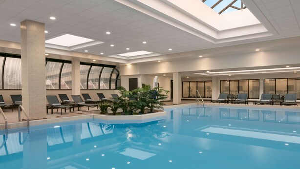 Una amplia piscina interior con sillones reclinables y techo de tragaluces.