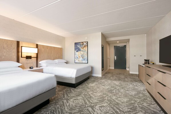 Habitación de hotel con dos camas, un cuadro grande, un televisor y un minibar.