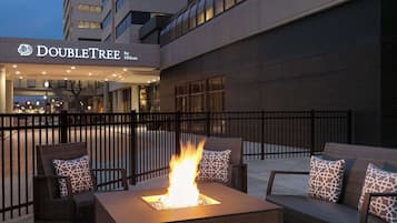 An outdoor seating area with a fire feature, a DoubleTree by Hilton sign, and a brick building facade.