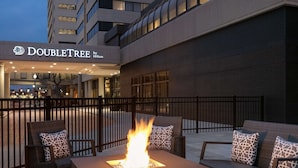 Exterior de un hotel DoubleTree by Hilton con un elemento decorativo de fuego en la zona de estar al aire libre.