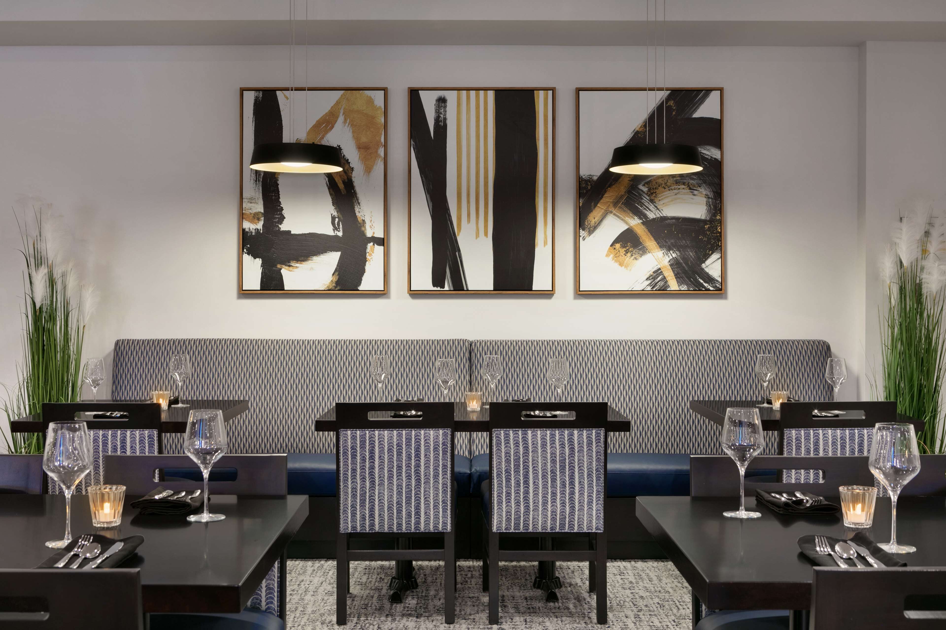A modern dining area with a dark wooden table, blue upholstered chairs, and abstract art on the wall.