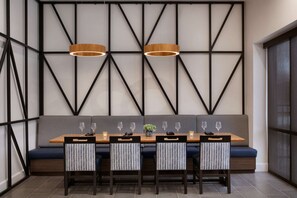 Un comedor moderno con una mesa de madera, sillas estampadas y un banco con cojines.