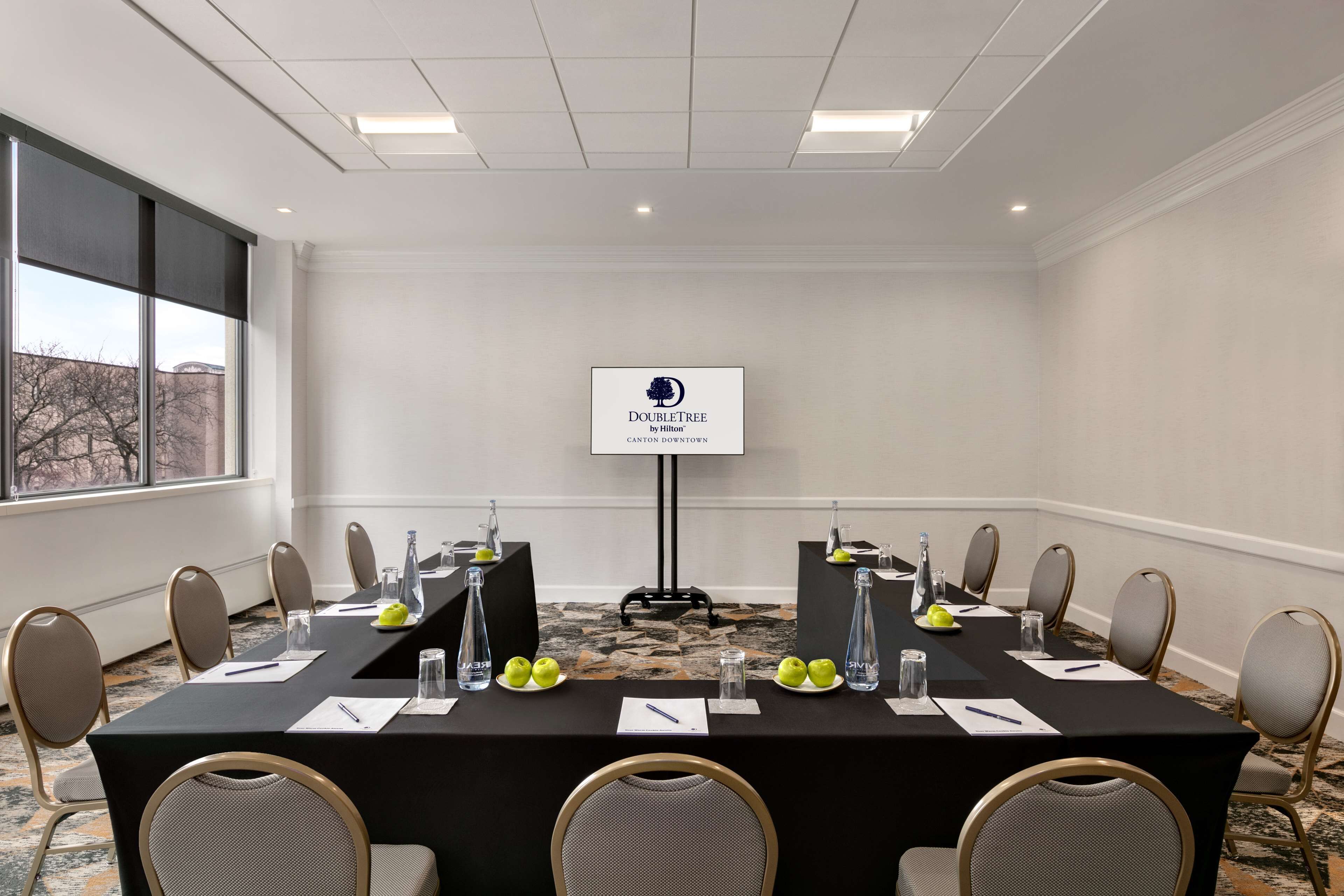 Ett konferensrum med ett svart bord, stolar och en skylt med texten ”DOUBLETREE by Hilton CANTON DOWNTOWN ”.