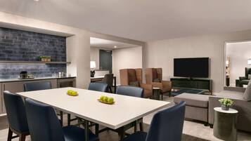 Una sala moderna con comedor, cocina y televisor.