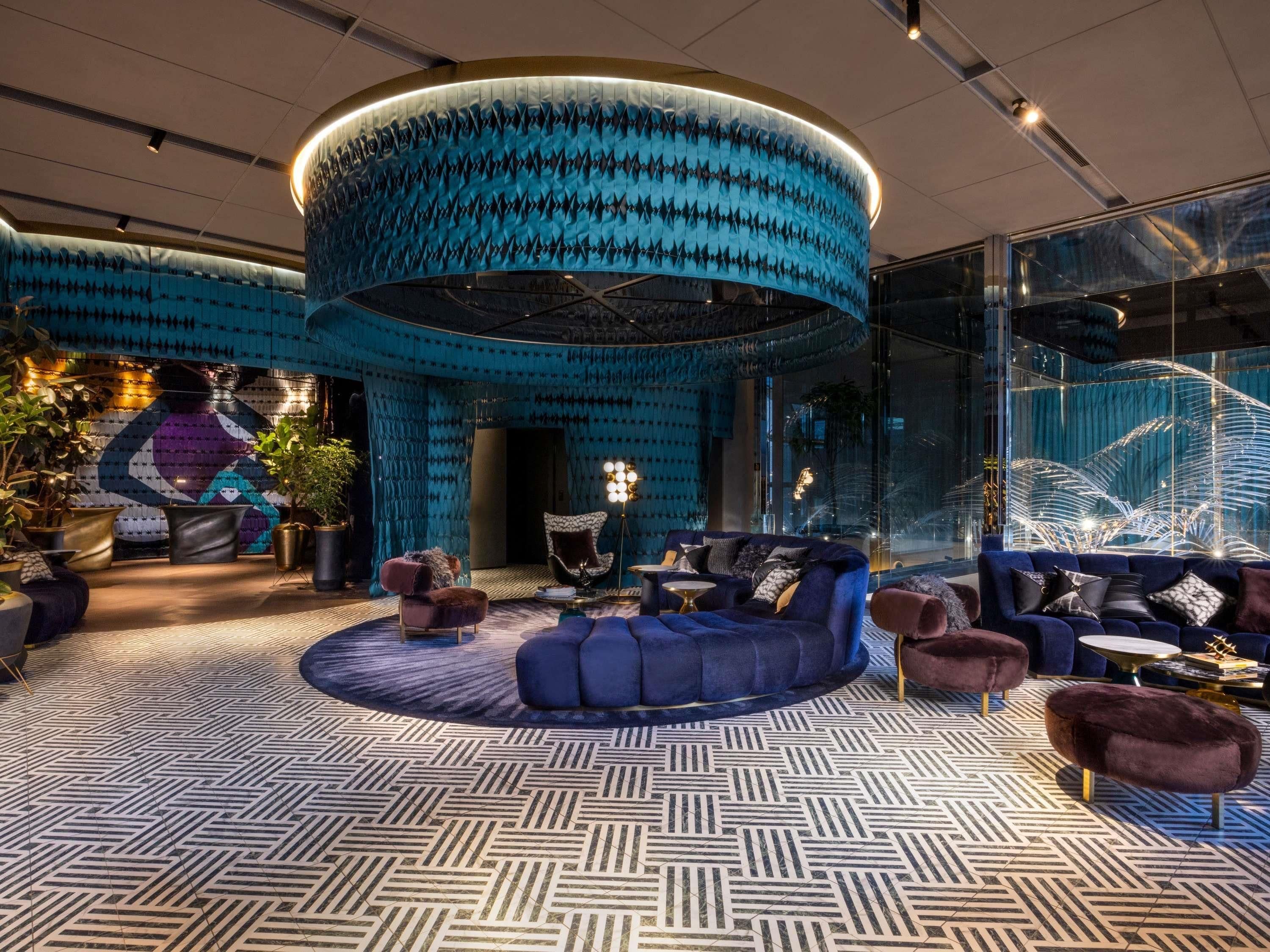 A modern interior with a circular blue wall, seating area, and patterned flooring.