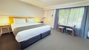 A hotel room with a large bed, bedside tables with lamps, a desk with two chairs, and a window with curtains. - Best Western Burnie Murchison Lodge (Somerset)
