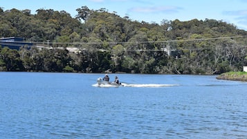 A boat on a calm lake with a forested hill in the background.