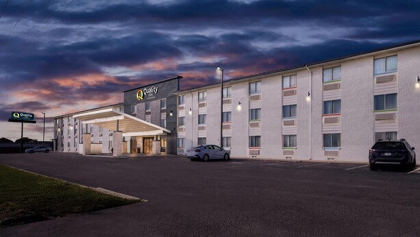 A hotel with a modern facade, multiple parking spaces, and a well-lit entrance.