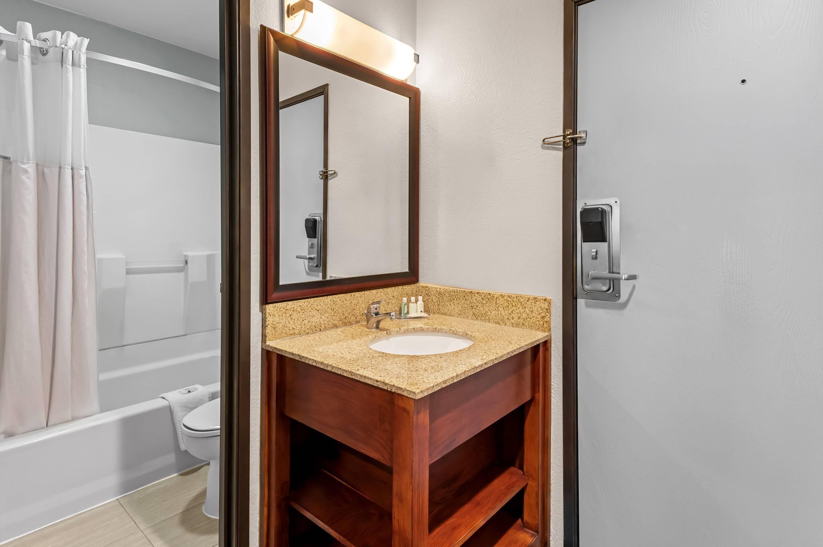 A bathroom with a wooden vanity, a sink, and a mirror.