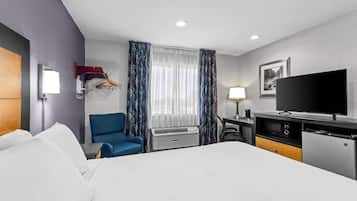 Una habitación de hotel con cama, escritorio, silla, televisor y armario.