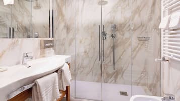 Un baño moderno con ducha envuelta en vidrio, una bañera independiente y un tocador con espejo y lavabo.