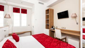 Una camera d'albergo con un letto, una scrivania, una TV e un armadio.