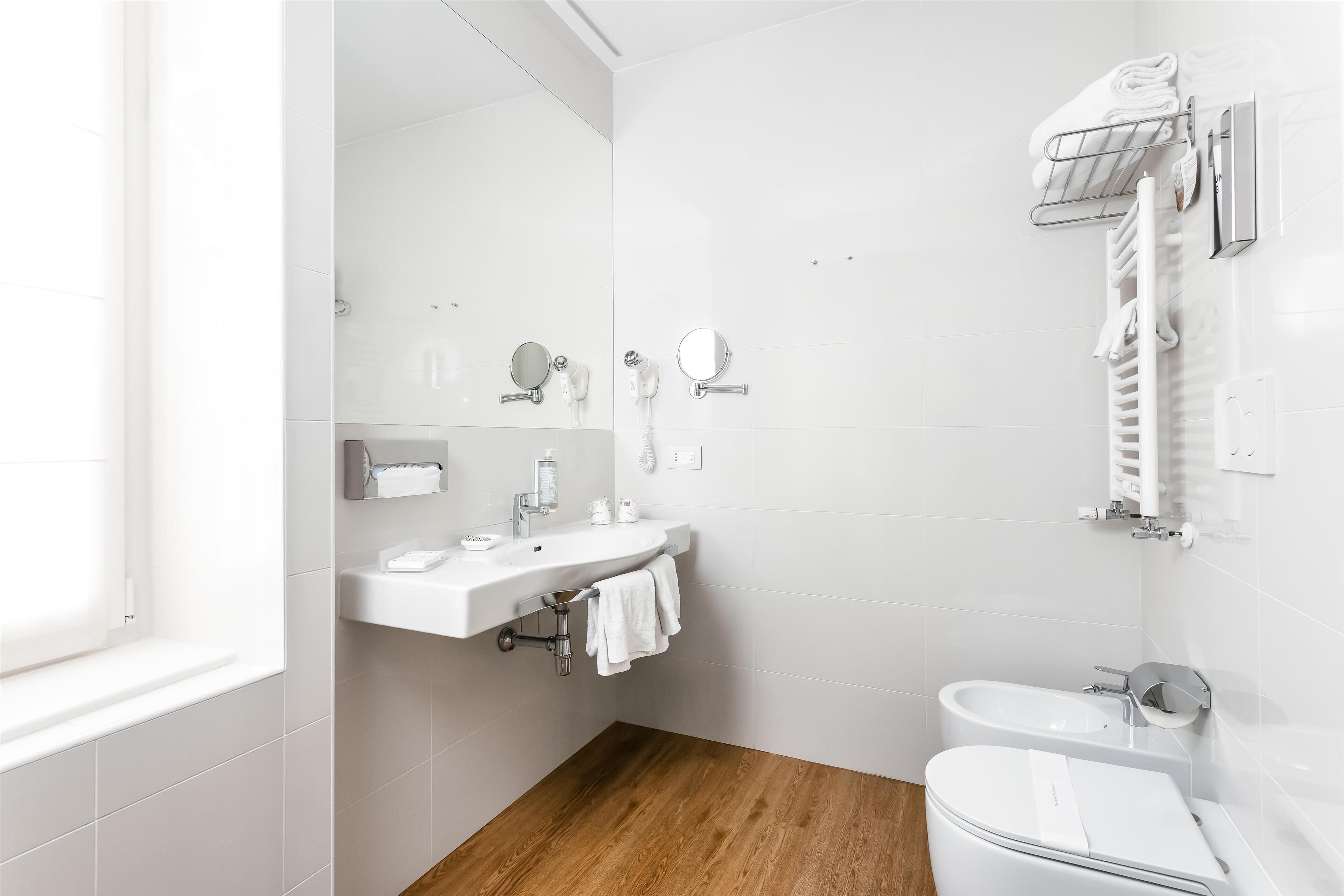 A modern bathroom with a white sink, mirror, and toilet.