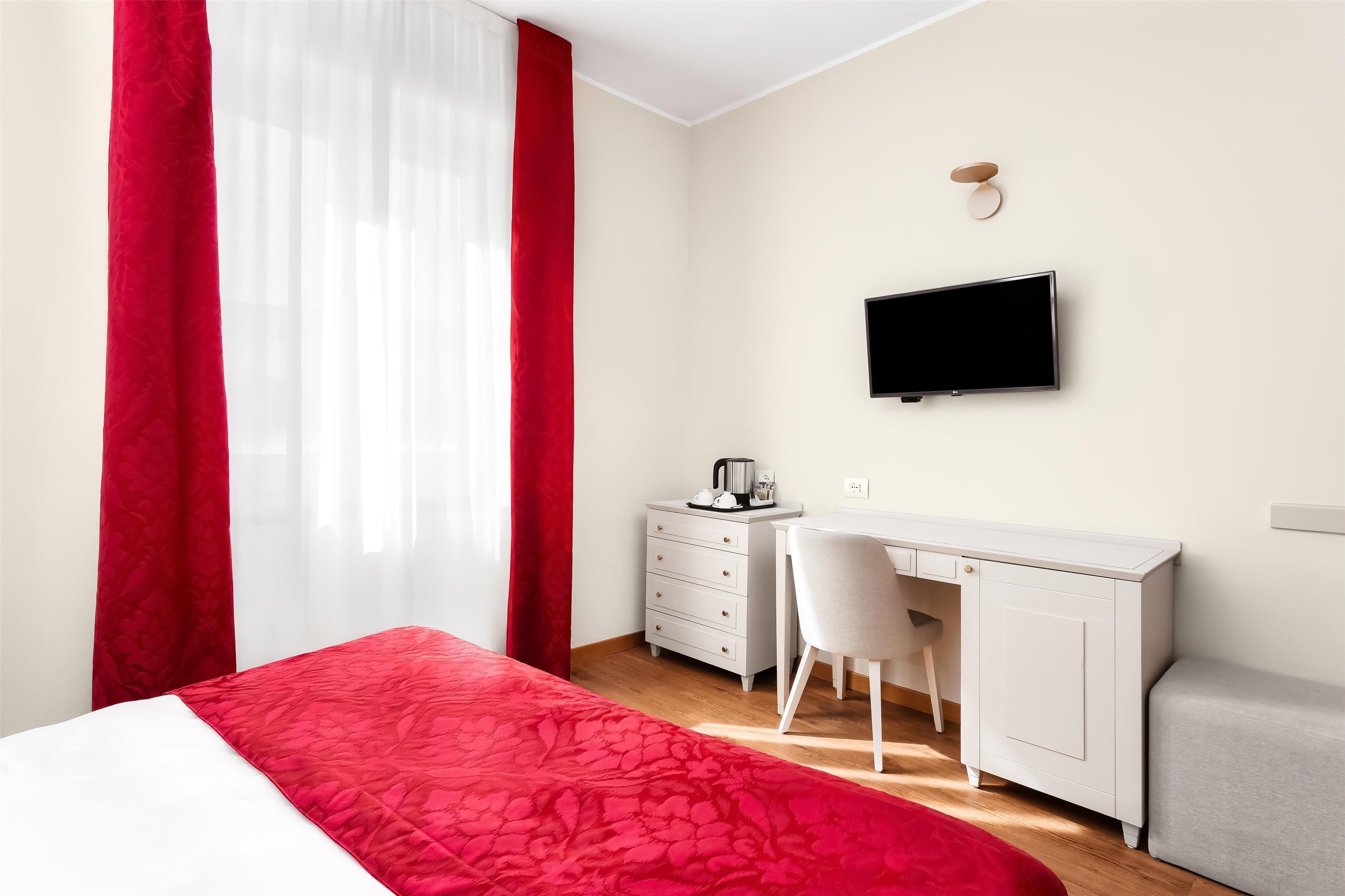 Een slaapkamer met een bed, een bureau en een televisie.
