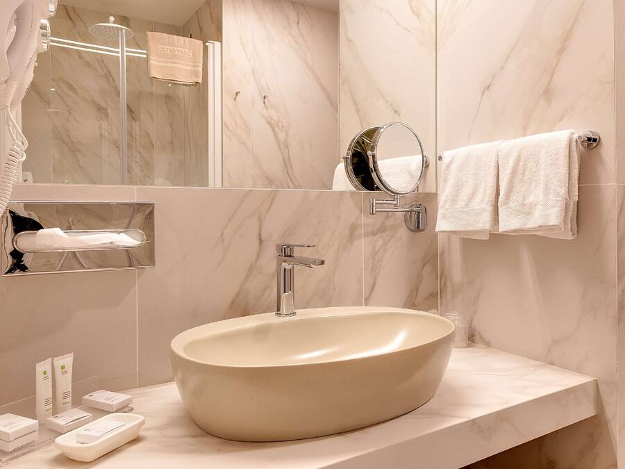 A modern bathroom with a large oval sink, a handheld showerhead, a mirror, and a towel rack.