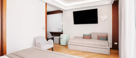 Un dormitorio moderno con cama, sofá, escritorio y televisión.