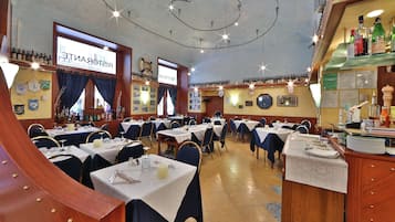 Ein Restaurant mit mehreren Tischen und Stühlen, einer Bar mit Flaschenauswahl und einer Speisekarte.