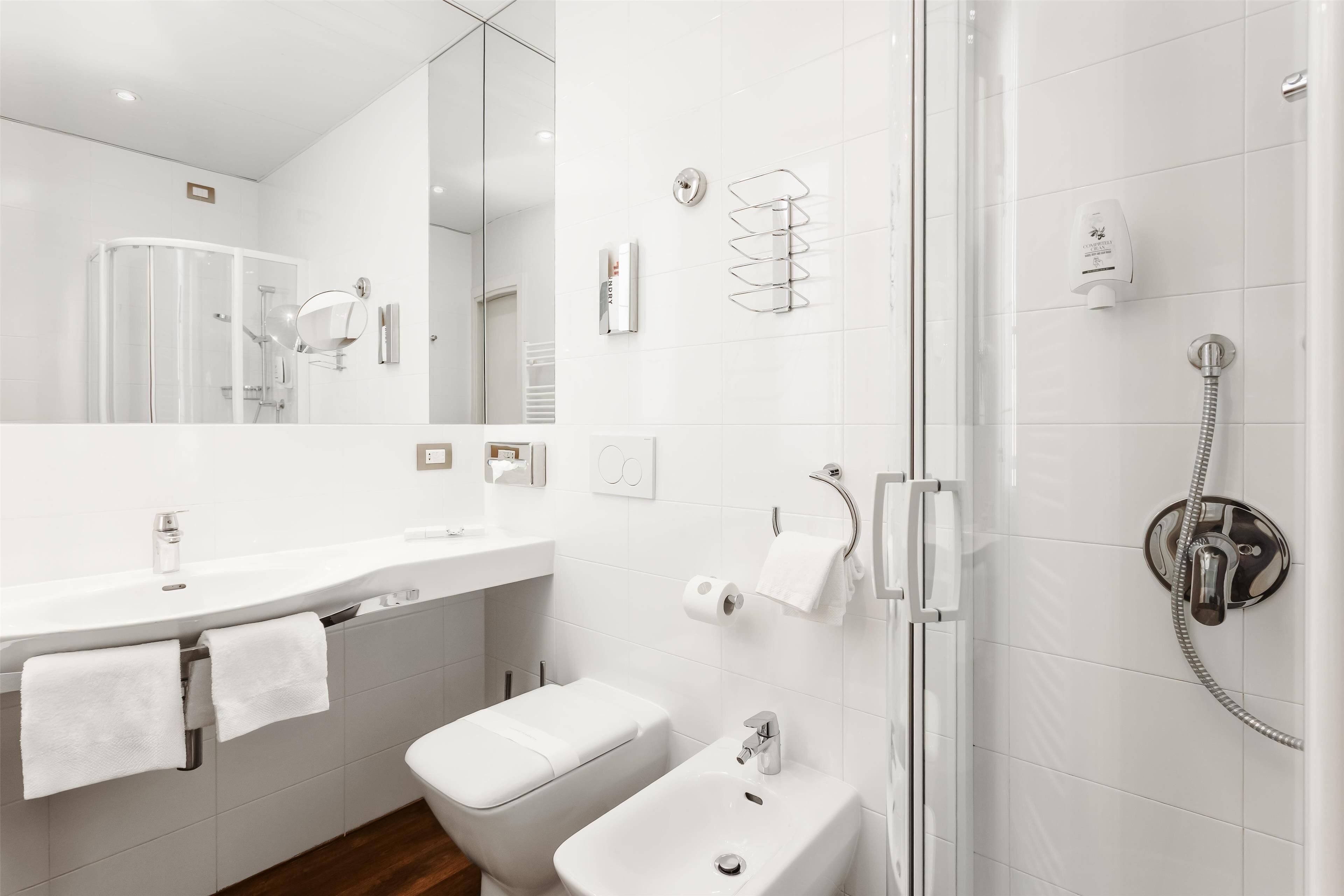 Un bany modern amb un cubicle de dutxa de vidre, un lavabo blanc i un vàter.