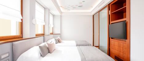 Un dormitorio moderno con dos camas, un televisor y un armario de madera.