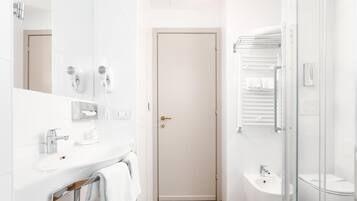 A modern bathroom with a white sink, a mirror, a towel rack, a shower area, and a toilet.