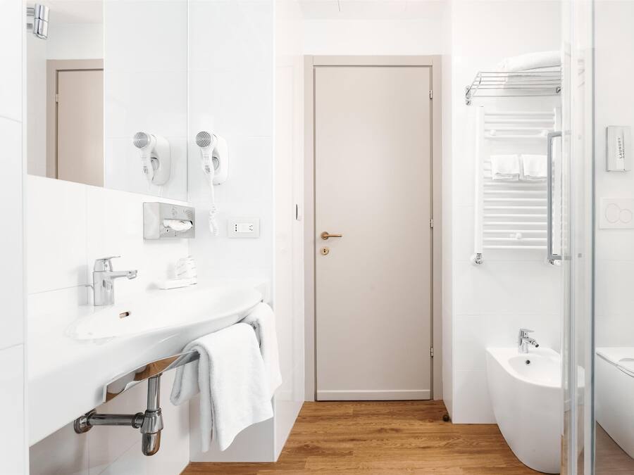 A modern bathroom with a white sink, a mirror, a towel rack, a shower area, and a toilet.
