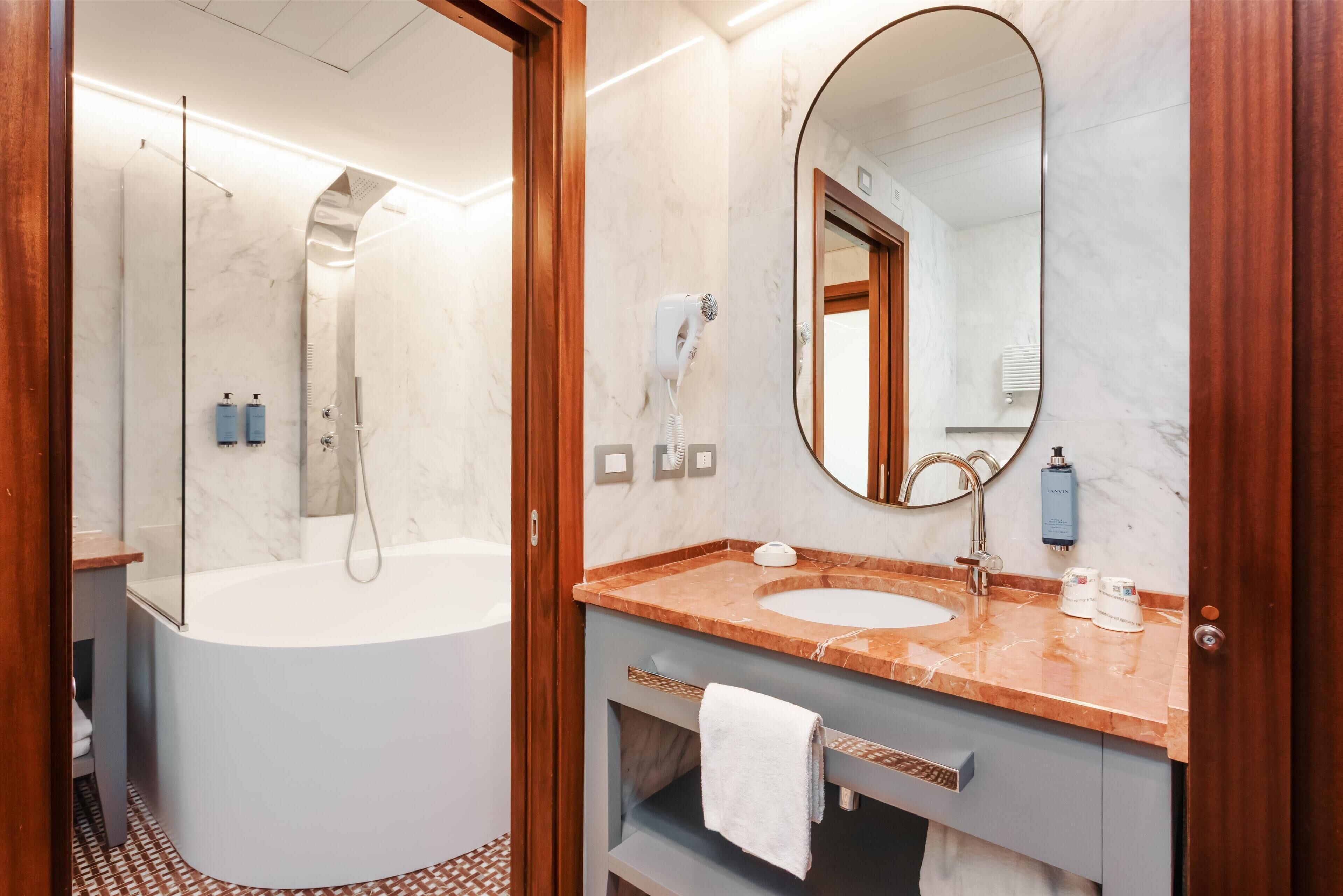 Een moderne badkamer met een bad, een wastafel, een spiegel en een douche.