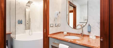Une salle de bain moderne équipée d’une baignoire, d’un lavabo, d’un miroir et d’une douche.