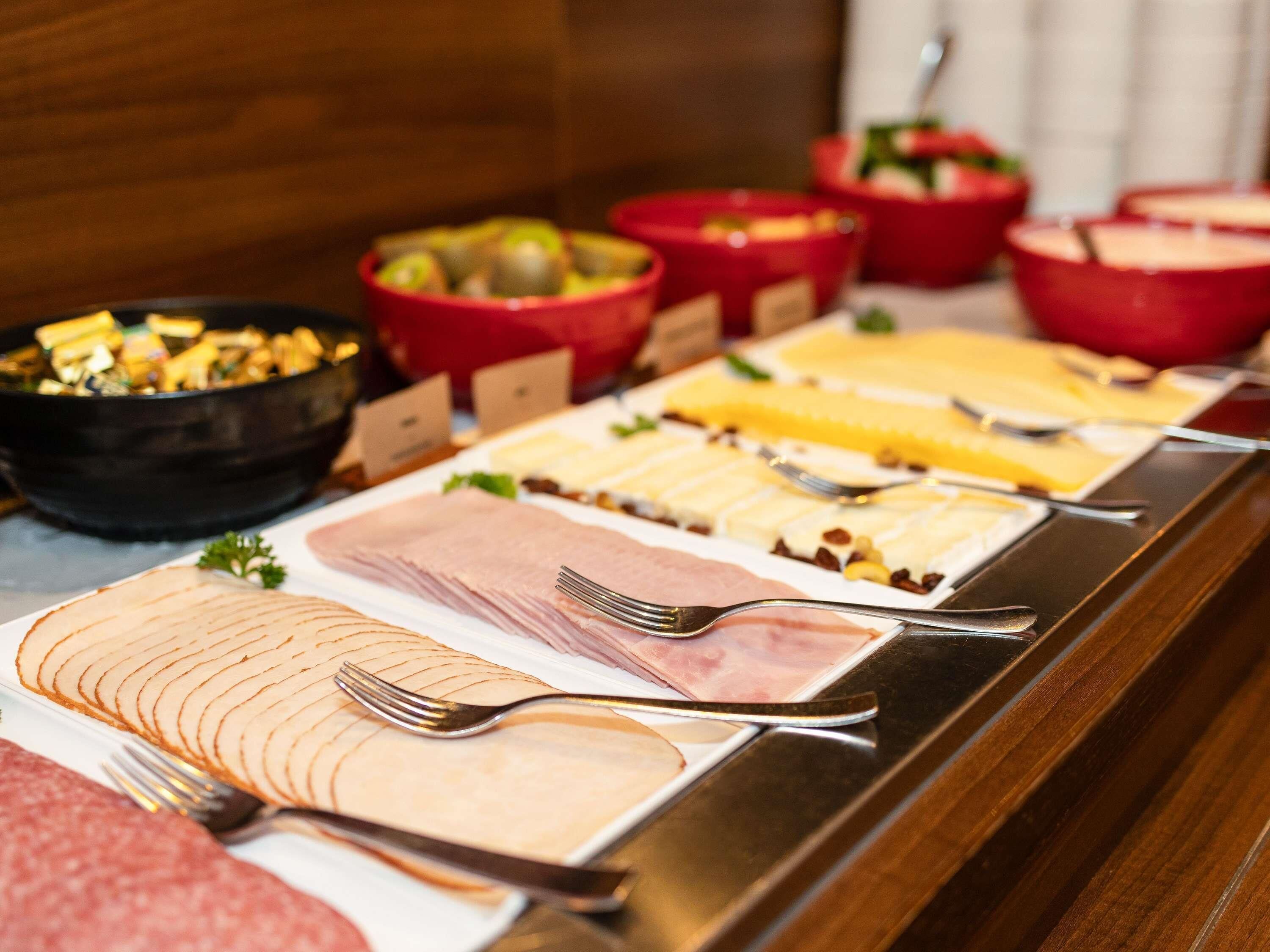 A buffet with various food items including sliced meats, cheeses, and salads.