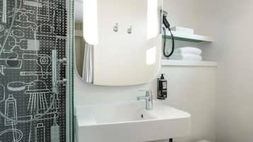 Une salle de bain moderne avec une douche à parois de verre, un lavabo blanc, un miroir et des toilettes.