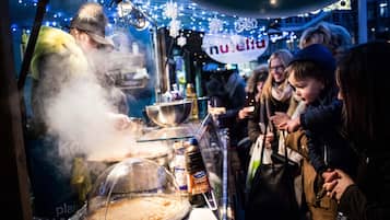 A street food vendor preparing food with steam rising from the cooking area.