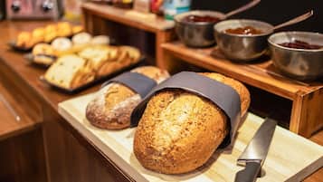 Verschiedene Brotsorten und Marmeladen auf einer Holztischplatte.