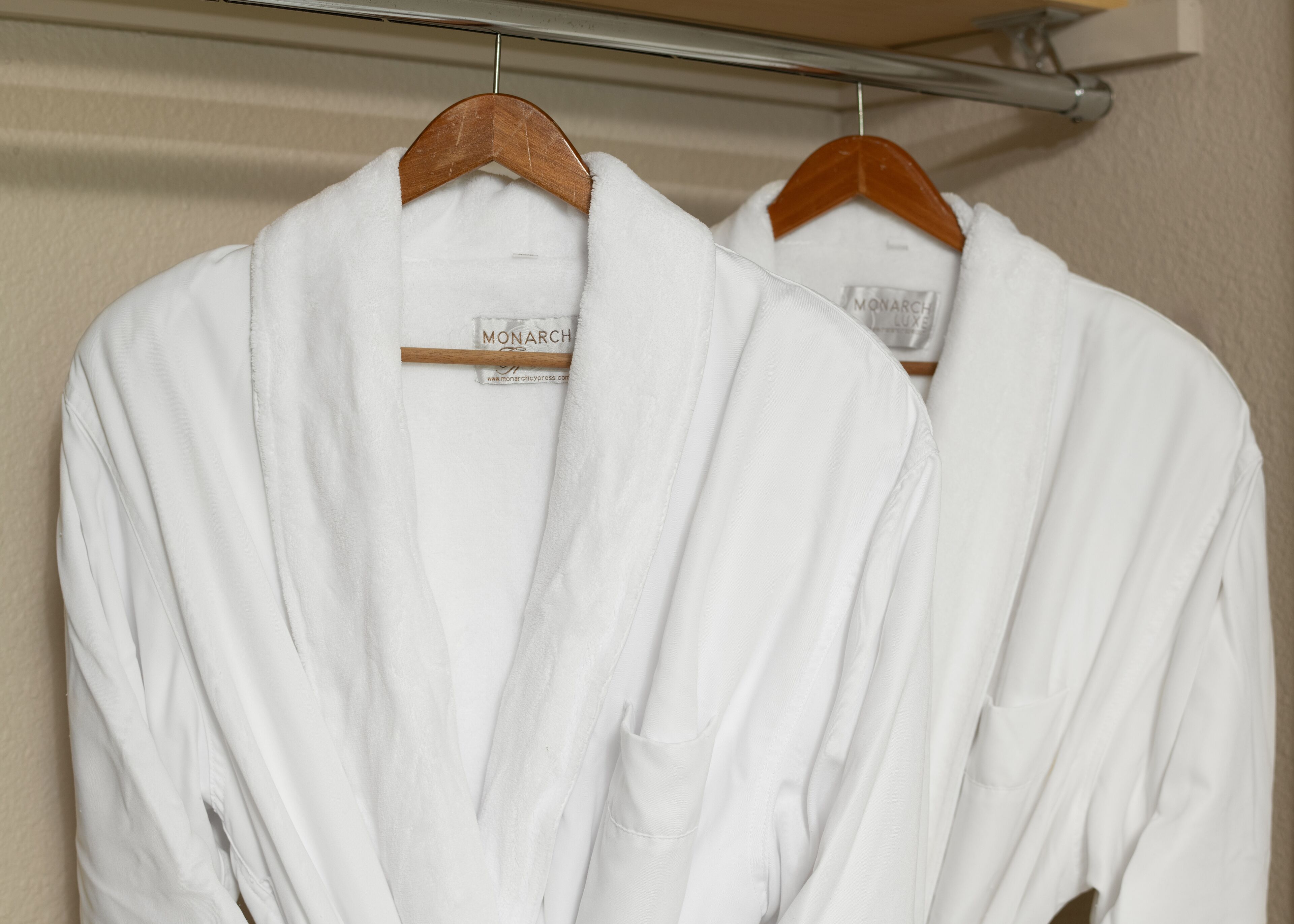 Deux robes blanches sont suspendues à un portant métallique dans une pièce.