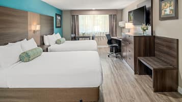 A hotel room with two beds, a desk, a chair, a TV, and a small bench.