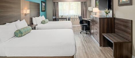 A hotel room with two beds, a desk, a chair, a TV, and a small bench.