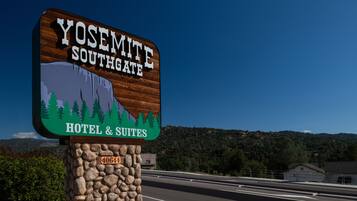 Une enseigne pour l’hôtel Yosemite Southgate Hotel & Suites, avec une illustration représentant une montagne et un arbre.