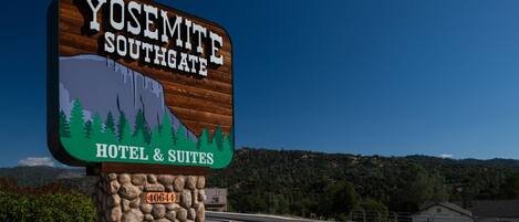 A sign for Yosemite Southgate Hotel & Suites with a mountain and tree graphic.