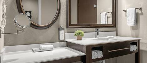 Un baño moderno con un espejo grande, un lavamanos y un mueble de tocador con un perchero para toallas.