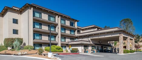 A multi-story hotel with a covered entrance and a landscaped driveway.